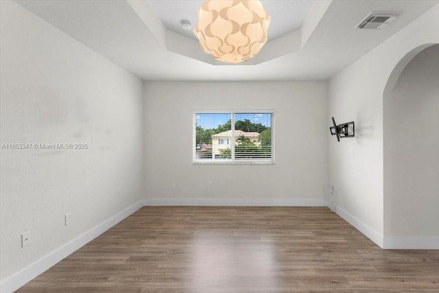 unfurnished room featuring hardwood / wood-style flooring and a tray ceiling