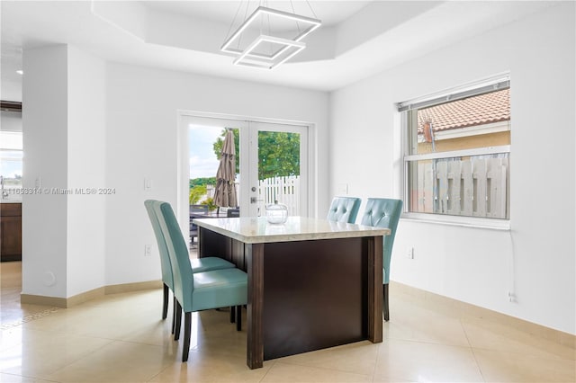 tiled dining space with plenty of natural light, french doors, and a tray ceiling