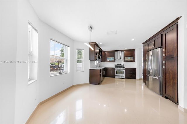 kitchen featuring wall chimney exhaust hood, sink, hanging light fixtures, appliances with stainless steel finishes, and dark brown cabinets