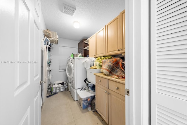 laundry room featuring cabinets, a textured ceiling, light tile patterned floors, and washing machine and dryer