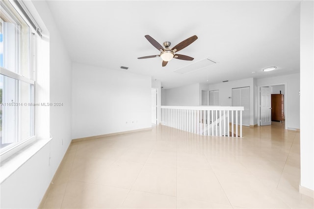 empty room featuring light tile patterned flooring, plenty of natural light, and ceiling fan