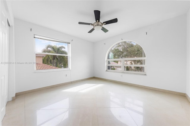 spare room featuring light tile patterned floors, a wealth of natural light, and ceiling fan