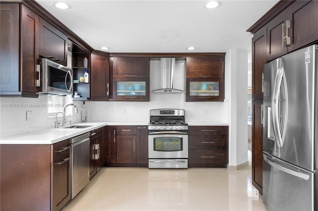 kitchen featuring light tile patterned floors, sink, dark brown cabinets, wall chimney range hood, and appliances with stainless steel finishes