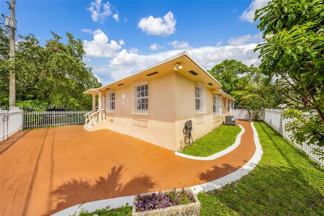 rear view of house with a fenced backyard, a lawn, and stucco siding