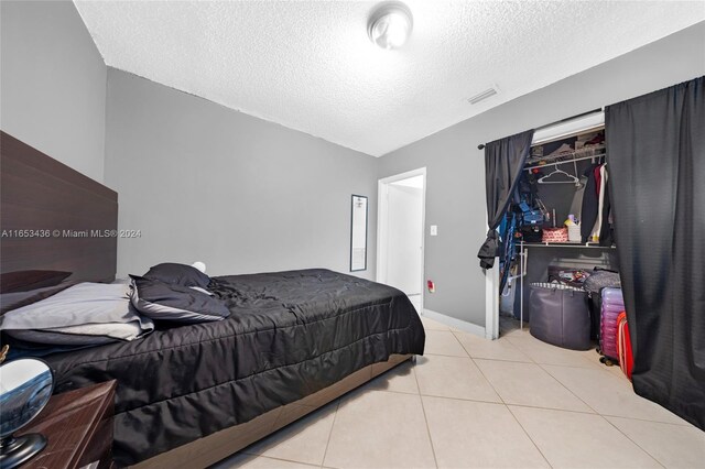 bedroom featuring a textured ceiling, light tile patterned floors, and lofted ceiling