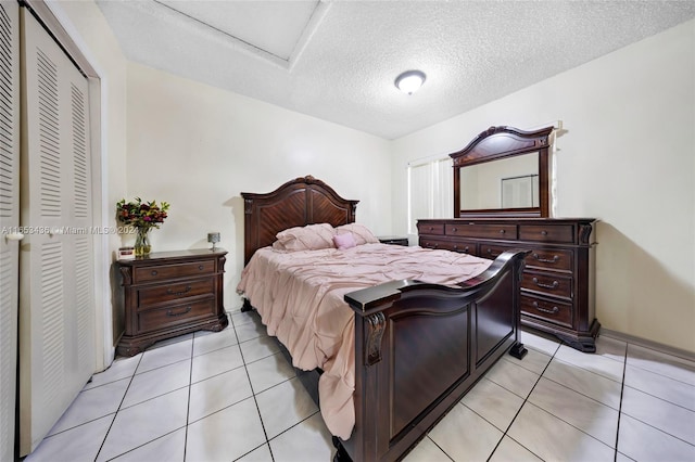 bedroom with a closet, light tile patterned flooring, and a textured ceiling