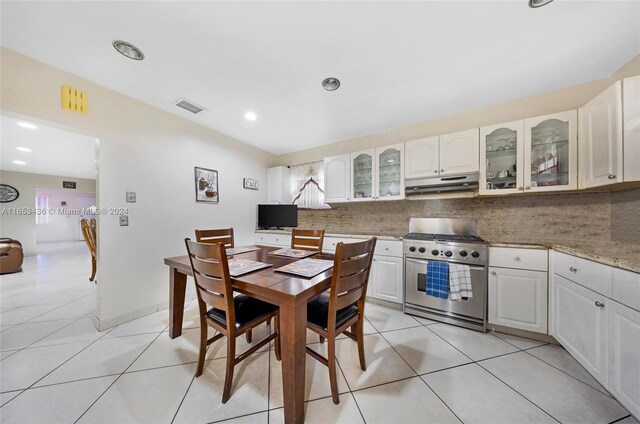 kitchen with light stone countertops, high end stainless steel range, light tile patterned floors, decorative backsplash, and white cabinetry