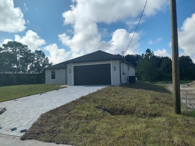 view of side of property with a garage, central AC unit, and a yard