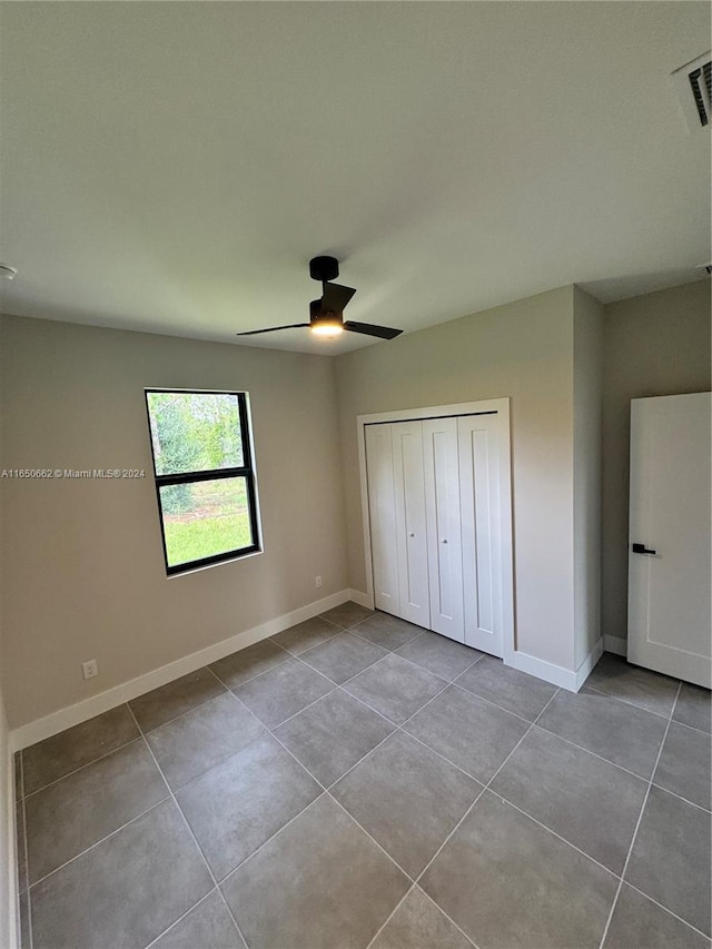 unfurnished bedroom with ceiling fan, a closet, and tile patterned floors