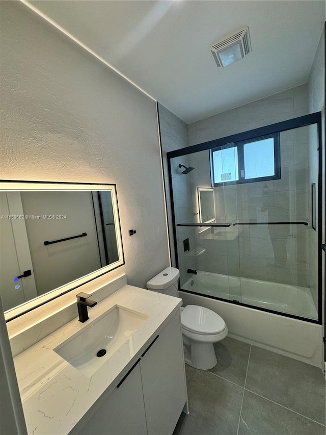 full bathroom with shower / bath combination with glass door, vanity, toilet, and tile patterned floors