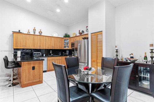 tiled dining area featuring sink and high vaulted ceiling