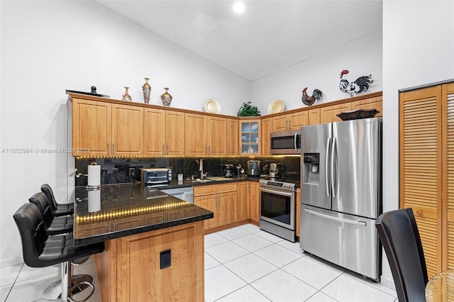 kitchen featuring a breakfast bar area, appliances with stainless steel finishes, kitchen peninsula, high vaulted ceiling, and light tile patterned flooring