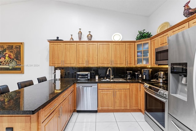 kitchen with a breakfast bar area, backsplash, appliances with stainless steel finishes, sink, and light tile patterned flooring