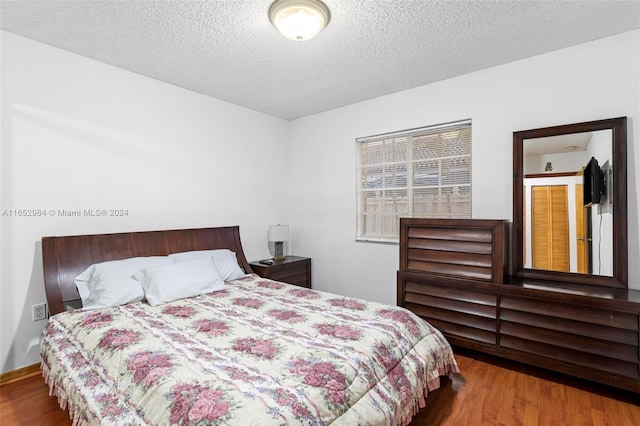 bedroom with a textured ceiling and wood-type flooring