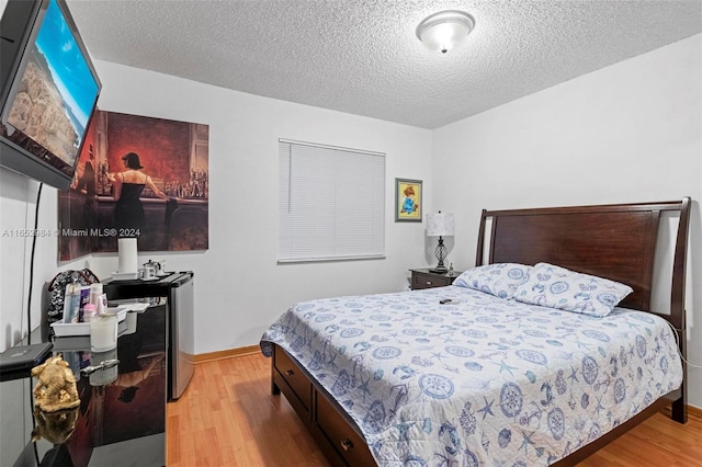 bedroom with a textured ceiling and light hardwood / wood-style floors