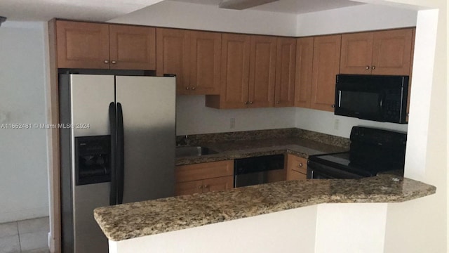 kitchen with black appliances, kitchen peninsula, light tile patterned floors, and stone counters