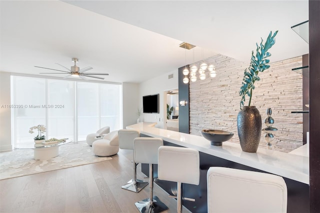 dining area featuring wood-type flooring, a breakfast bar area, hanging light fixtures, and ceiling fan