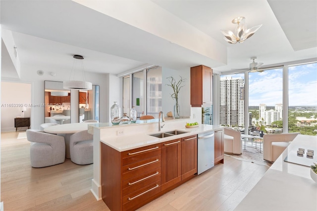 kitchen featuring light hardwood / wood-style flooring, hanging light fixtures, sink, and stainless steel dishwasher