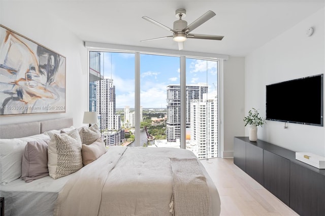 bedroom with ceiling fan, a wall of windows, and light wood-type flooring