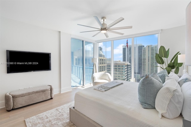 bedroom with ceiling fan, a wall of windows, light hardwood / wood-style floors, and access to outside