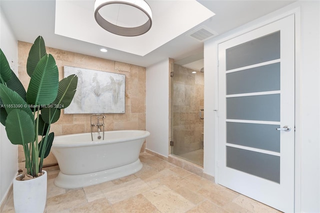 bathroom featuring independent shower and bath and tile walls