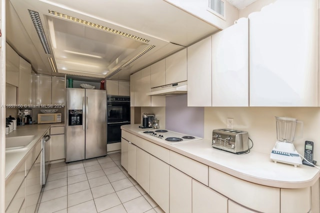 kitchen featuring appliances with stainless steel finishes, white cabinetry, sink, and light tile patterned flooring