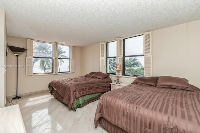 bedroom with a textured ceiling and light hardwood / wood-style flooring