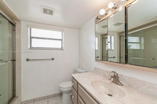 bathroom featuring tile patterned flooring, vanity, toilet, and a shower with shower door