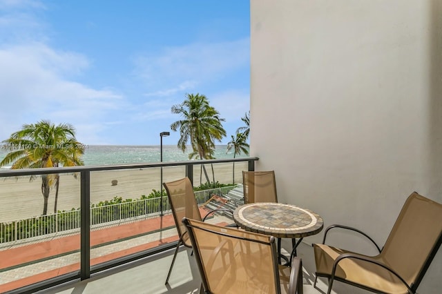 balcony featuring a view of the beach and a water view