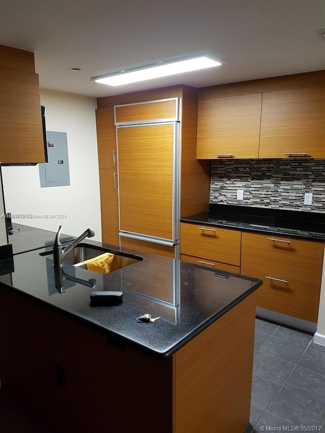 kitchen with dark tile patterned flooring, sink, decorative backsplash, and electric panel