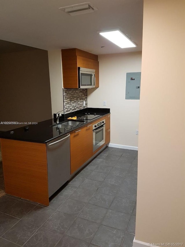 kitchen with electric panel, stainless steel appliances, tasteful backsplash, and sink