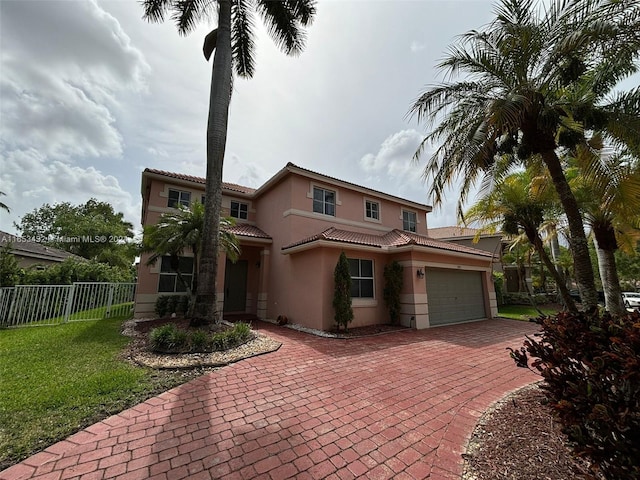 mediterranean / spanish home featuring a garage and a front lawn