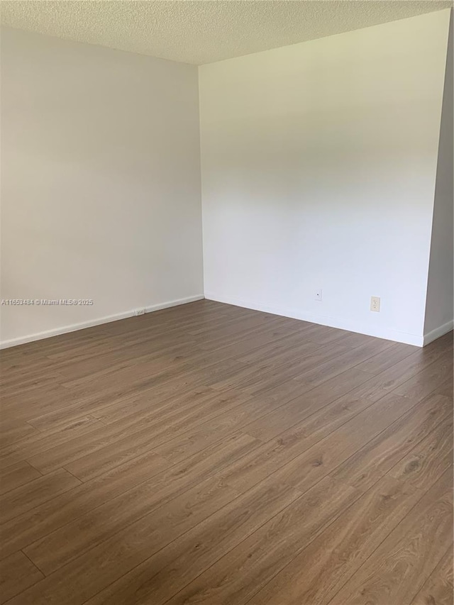 spare room with dark wood-type flooring and a textured ceiling