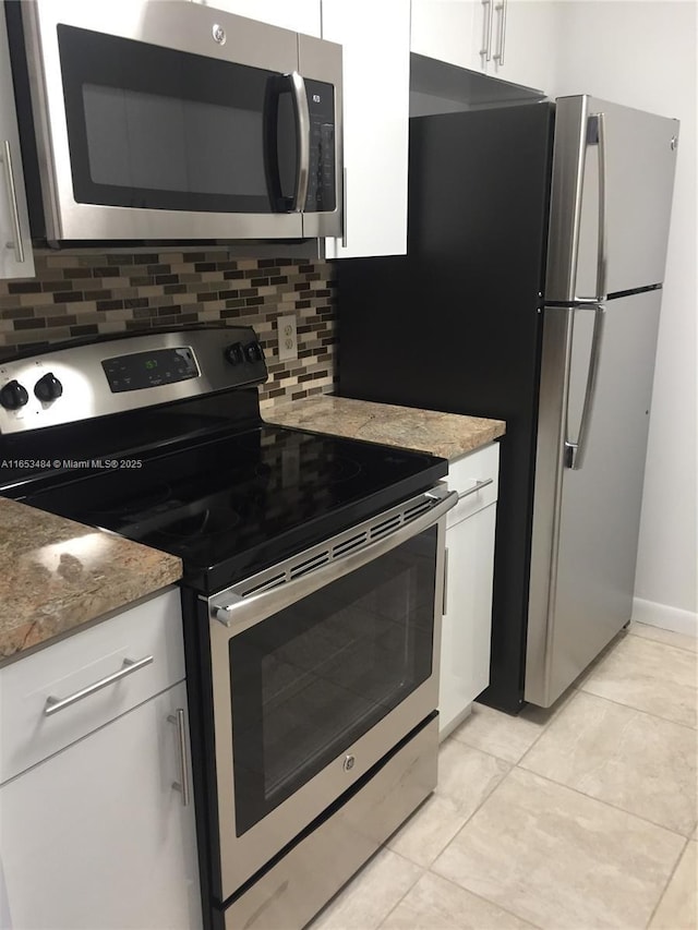 kitchen featuring white cabinetry, stainless steel appliances, light stone countertops, and decorative backsplash