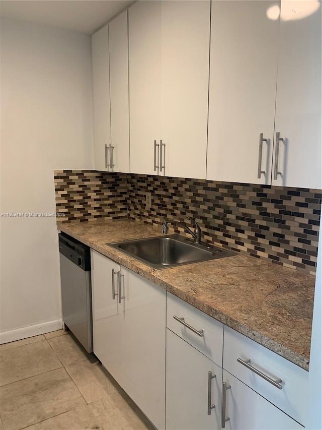 kitchen featuring light tile patterned flooring, white cabinetry, sink, backsplash, and stainless steel dishwasher