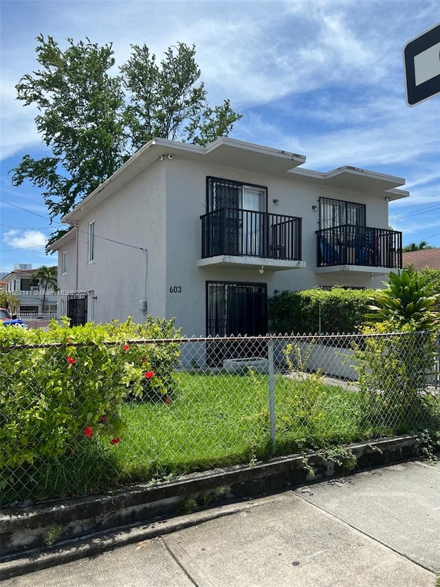 view of front of house with a balcony and a front yard