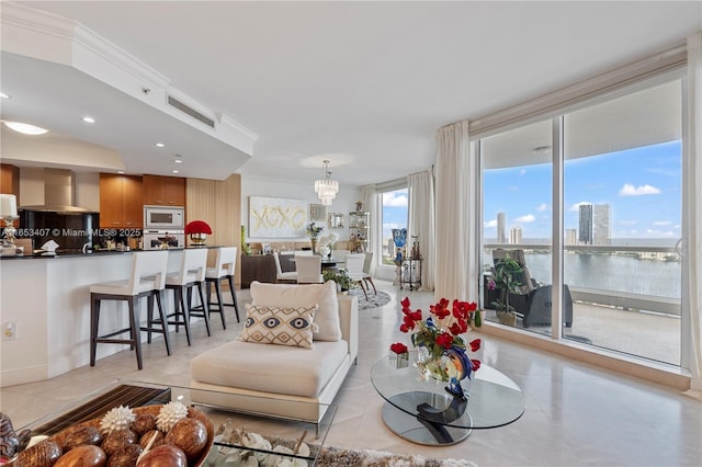 living room featuring light tile patterned floors, crown molding, a chandelier, and a water view