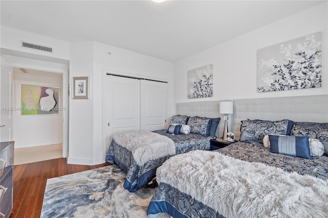 bedroom with dark hardwood / wood-style flooring and a closet