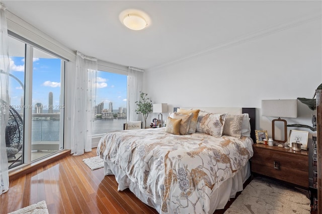 bedroom featuring a water view, wood-type flooring, crown molding, and access to outside