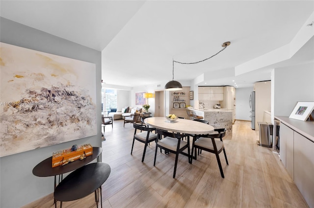 dining space featuring vaulted ceiling, sink, and light wood-type flooring