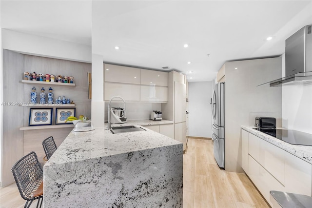 kitchen with light hardwood / wood-style flooring, light stone counters, stainless steel refrigerator, sink, and black electric cooktop