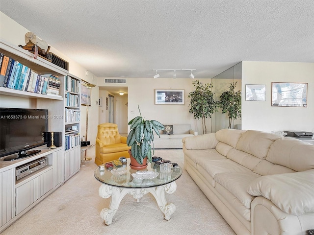 carpeted living room featuring track lighting and a textured ceiling