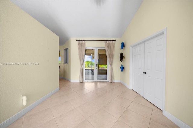 unfurnished bedroom featuring a closet, vaulted ceiling, light tile patterned floors, and access to outside