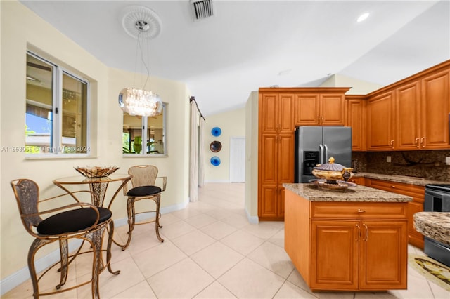 kitchen featuring stone counters, a center island, decorative backsplash, hanging light fixtures, and stainless steel refrigerator with ice dispenser