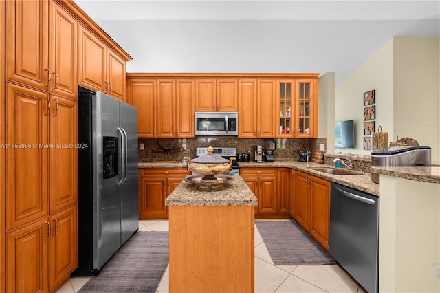 kitchen with a center island, appliances with stainless steel finishes, light stone counters, sink, and light tile patterned flooring