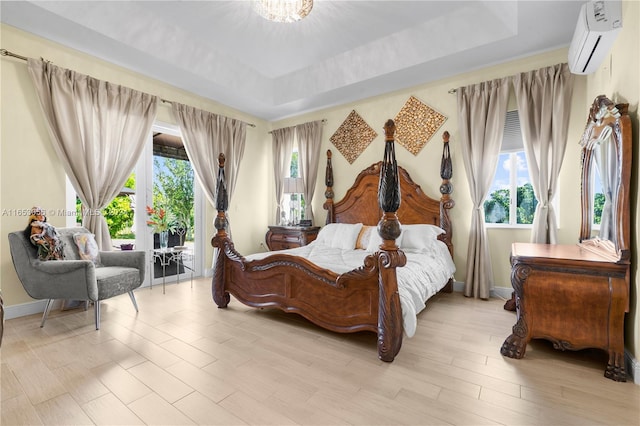 bedroom with a wall mounted AC, light hardwood / wood-style flooring, and a tray ceiling