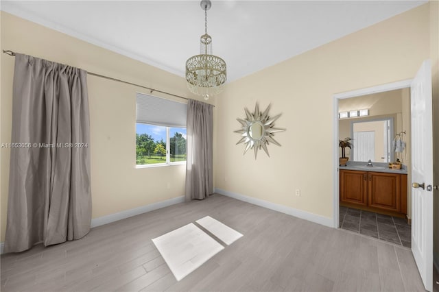 spare room featuring light hardwood / wood-style flooring, a chandelier, and sink