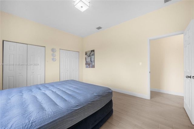 bedroom featuring two closets and light hardwood / wood-style floors