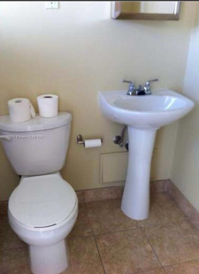 bathroom with toilet, sink, and tile patterned floors