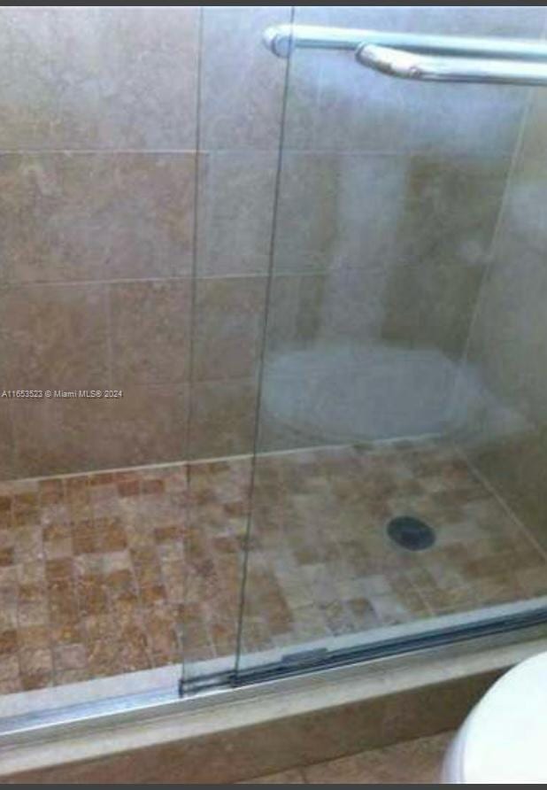 bathroom with a shower with door and toilet